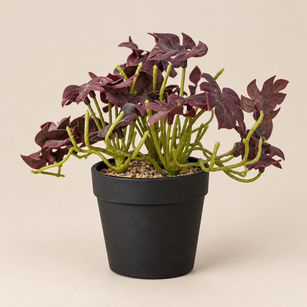 Mini faux foliage plant with burgundy leaves in black pot, three-quarter angle