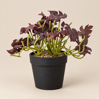 Mini faux foliage plant with burgundy leaves in black pot, three-quarter angle