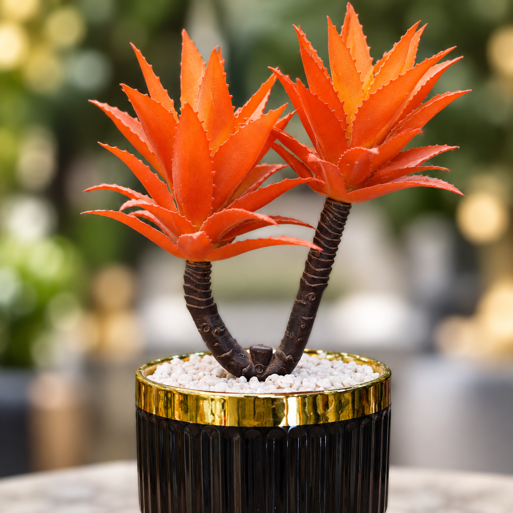 Close-up of faux orange aloe succulent in black and gold ceramic planter